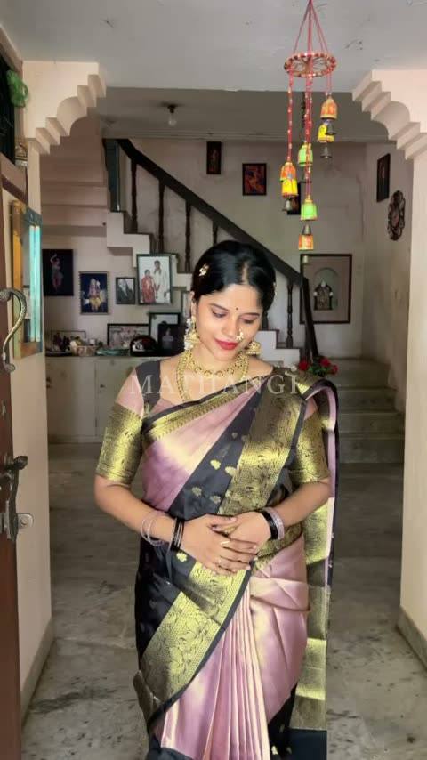 The rose and black zari saree held open before it is draped