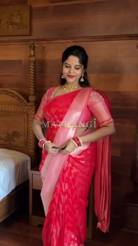 The coral and rose saree held open before it is draped